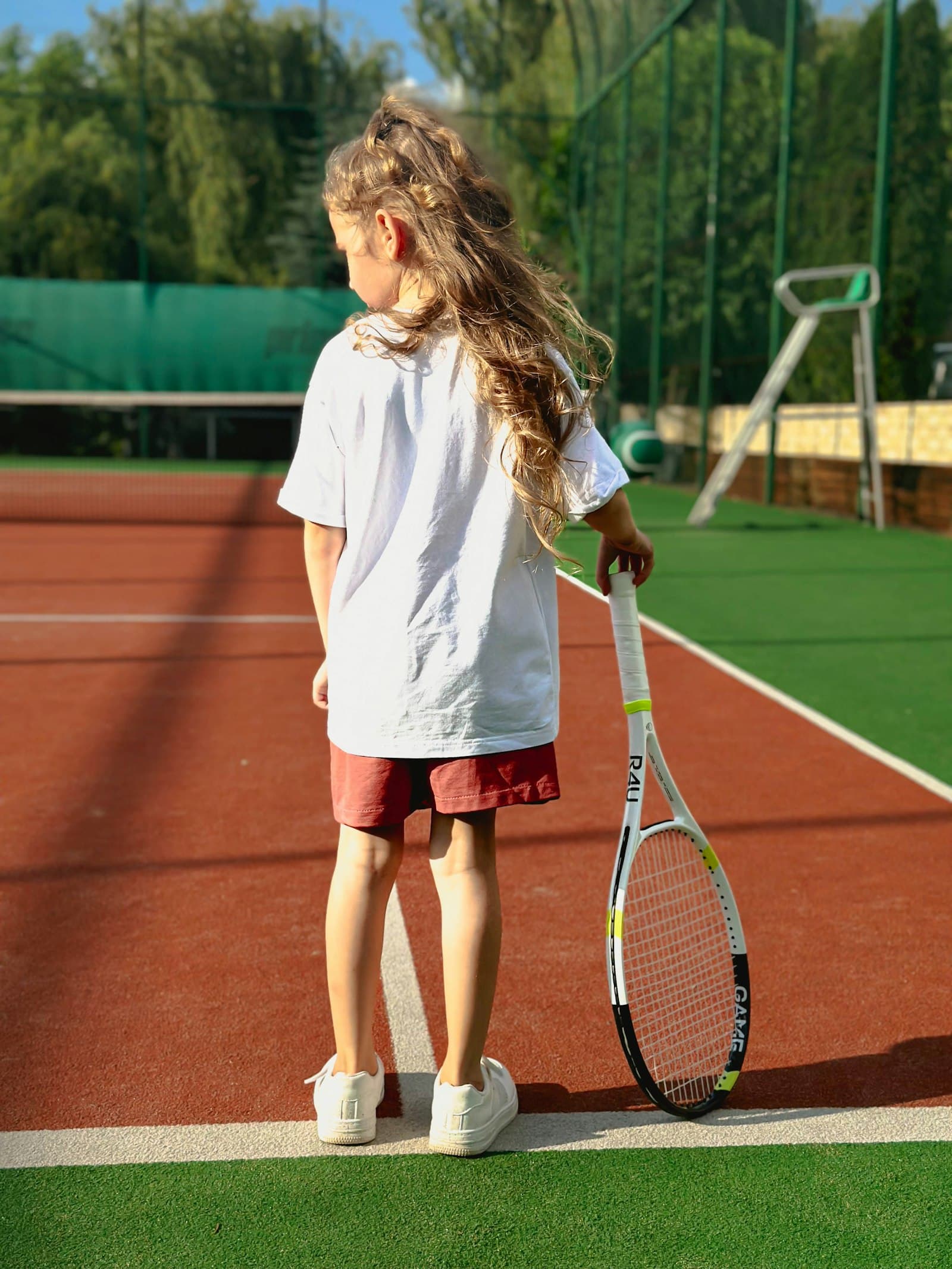 A young girl holding her racquet on court