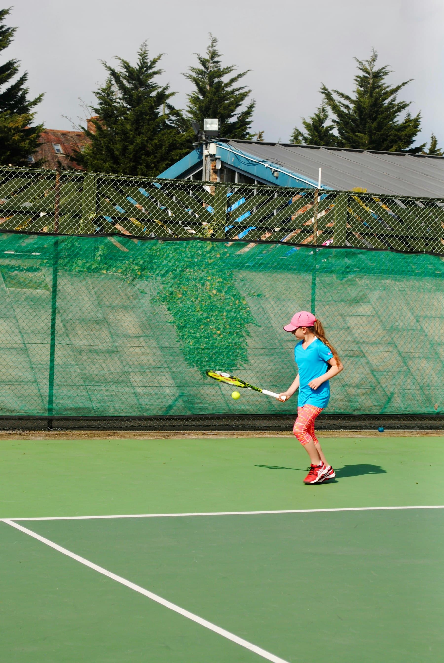 A girl hitting a forehand on a green court