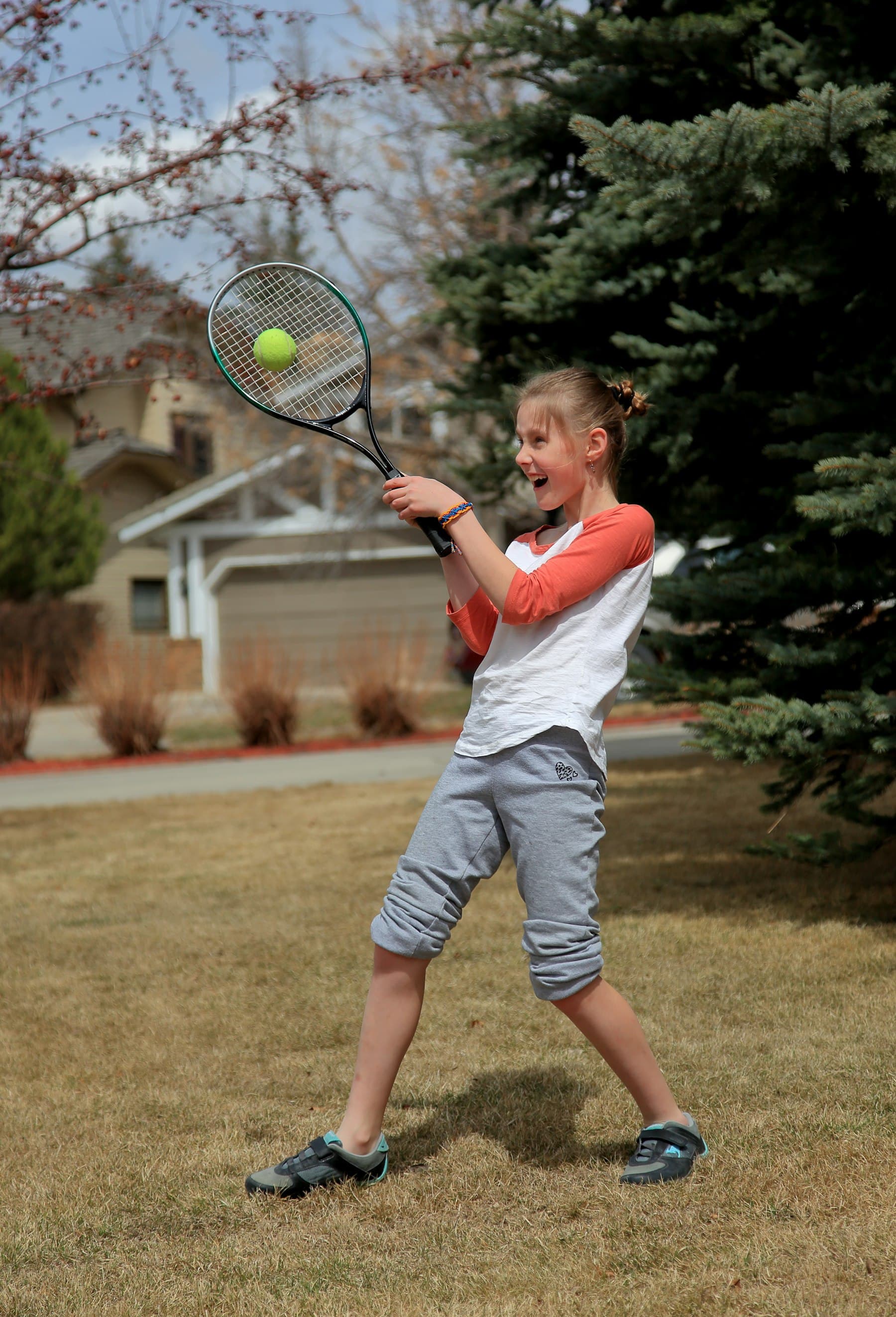 A girl laughing as she swings her racquet
