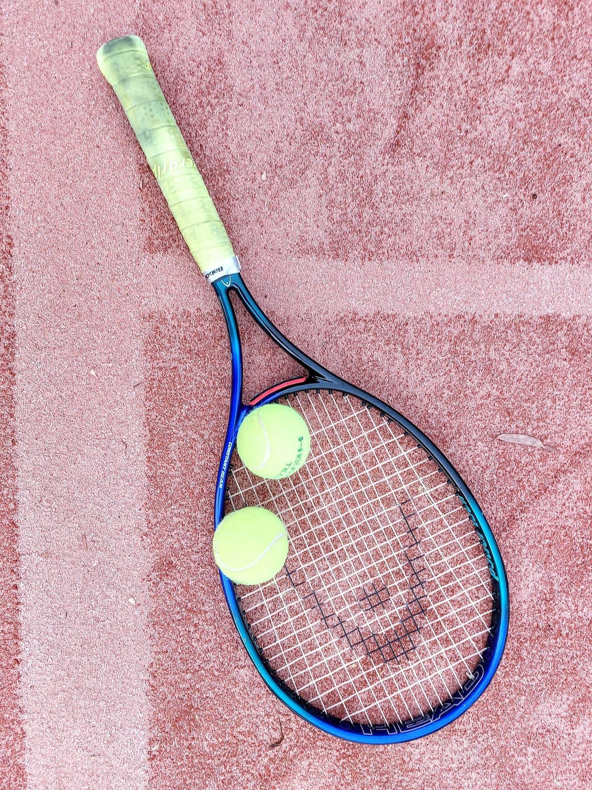 A racquet and two balls on a clay court