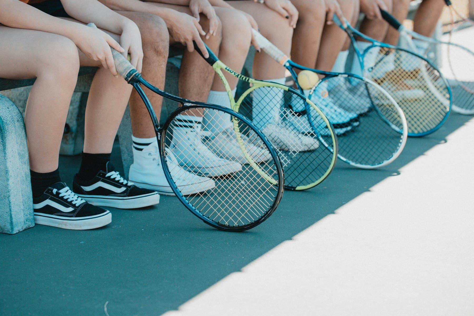 Kids sitting in a row with their racquets