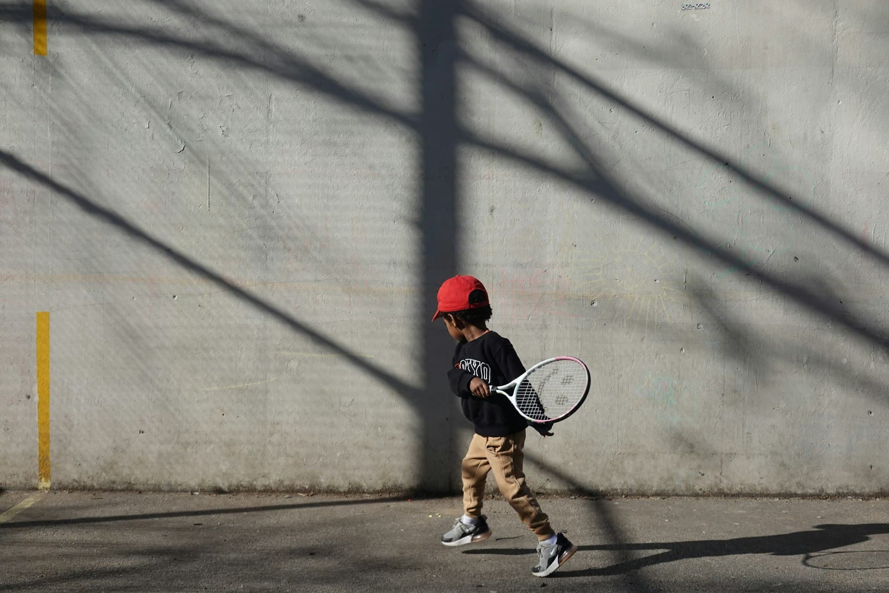 A small boy swinging at a ball by a wall